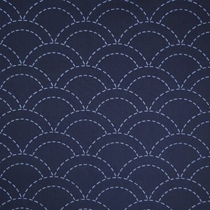 May include: A dark blue fabric with a white stitched pattern of overlapping semicircles. The pattern resembles scales.