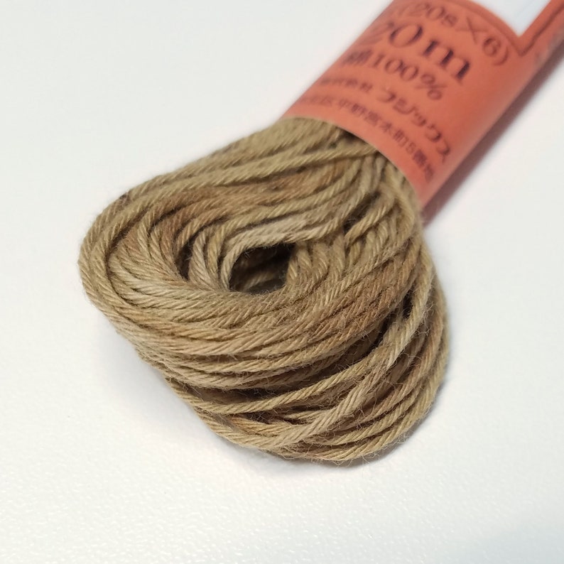 May include: A spool of brown embroidery floss with the text "20m 100% Cotton" on the label.