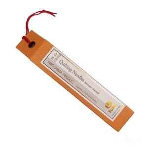 May include: A package of assorted quilting needles in sizes 8, 9, 10, and 12. The package is orange with gold lettering and a gold logo that says "Tsuba" and "Made in Japan".