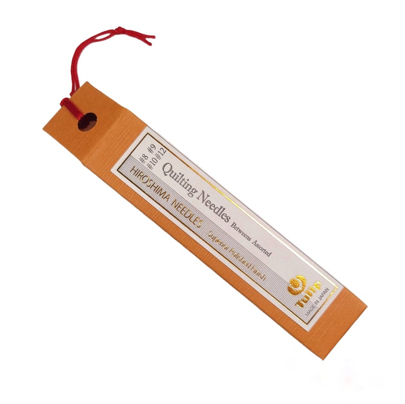 May include: A package of assorted quilting needles in sizes 8, 9, 10, and 12. The package is orange with gold lettering and a gold logo that says "Tsuba" and "Made in Japan".
