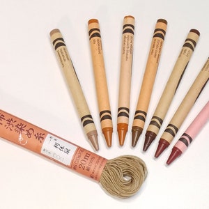 May include: A spool of 20 meters of 100% cotton thread in a natural beige color, labeled "柿渋染め糸体 0011 omaranto #6(20g&times;6) 20m 綿100%".  The thread is surrounded by eight crayons in various shades of brown, beige, and pink.