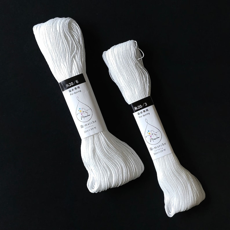 Puede incluir: Dos carretes de hilo de algod&oacute;n blanco para te&ntilde;ir, etiquetados con "糸20/6 染め専用 For dyeing -marche 20m&times;3かせ" y "糸20/3 染め専用 For dyeing -marche 20m&times;3かせ".