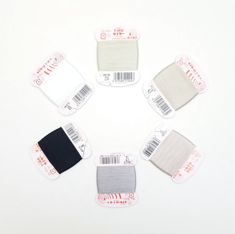 May include: Five spools of white, gray, and black thread with labels in Japanese. The labels include the text "40s TIRE" and "ワイヤー".