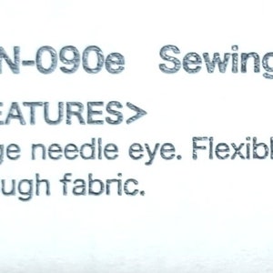 May include: A barcode label for sewing needles. The label reads "THN-090e Sewing Needles Assorted" and lists features: "Large needle eye. Flexible and warp resistant. Runs smoothly through fabric."