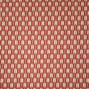 Puede incluir: Tela roja con un patrón geométrico blanco de flechas repetidas.