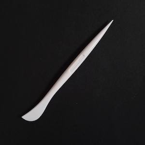 Puede incluir: Herramienta de escultura de plástico blanco con una punta puntiaguda y un extremo redondeado y plano. La herramienta mide aproximadamente 38 cm de largo.