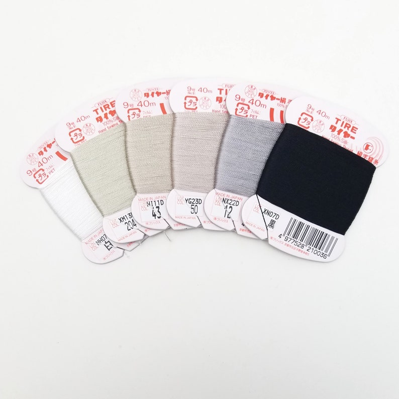 May include: Seven spools of thread in various shades of beige, gray, and black. Each spool is labeled "TIRE" and has a length of 9 meters (40 yards).