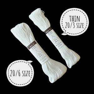 Puede incluir: Dos carretes de hilo de bordar blanco, uno etiquetado con "糸20/6 染め専用 For dyeing" y el otro con "糸20/3 染め専用 For dyeing". Los carretes est&aacute;n etiquetados con la marca "r.marche".