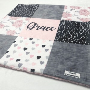 May include: A pink and gray patchwork baby blanket with a floral pattern, hearts, and polka dots. The blanket is personalized with the name "Grace".