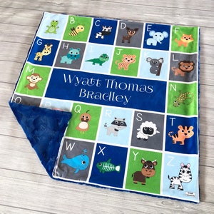May include: A blue, green, and gray baby blanket with a personalized name "Wyatt Thomas Bradley" and an alphabet pattern featuring animal illustrations.