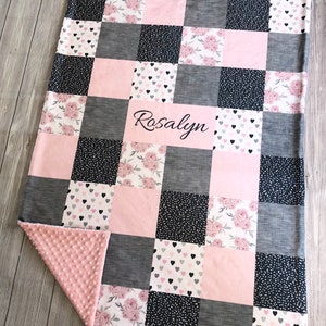 May include: A pink and gray patchwork baby blanket with a floral and heart print. The blanket is personalized with the name "Rosalyn".