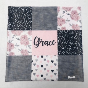 May include: A pink and gray patchwork baby blanket with a floral pattern, hearts, and polka dots. The blanket is personalized with the name "Grace".