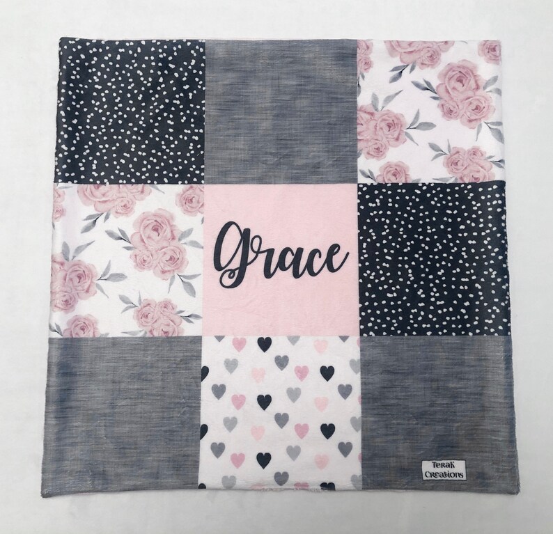 May include: A pink and gray patchwork baby blanket with a floral pattern, hearts, and polka dots. The blanket is personalized with the name "Grace".