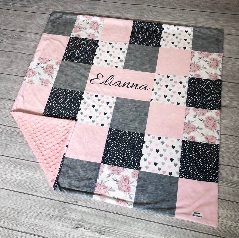 May include: A pink and gray patchwork baby blanket with a floral and heart print. The blanket is personalized with the name "Elianna".