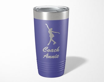 May include: A purple stainless steel tumbler with a silver lid. The tumbler has a silhouette of a figure ice skating and the text "Coach Annie" on it.