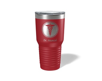 Könnte beinhalten: Ein roter Edelstahlbecher mit einem silbernen Deckel. Der Becher hat ein silbernes medizinisches Symbol mit einer Schlange und Flügeln in einem Kreis und den Text "Dr. Hamid" unter dem Symbol.