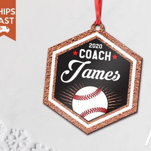 May include: A hexagonal baseball-themed Christmas ornament with a red and white baseball, gold glitter, and the text "2020 COACH James" in black.