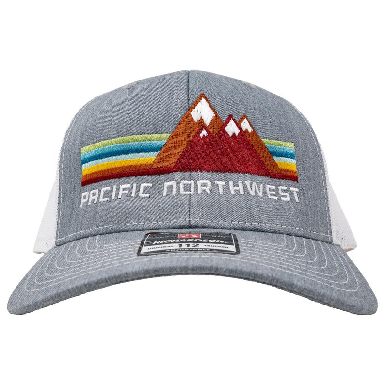 May include: A gray and white trucker hat with a red, orange, and yellow mountain range design and the text "PACIFIC NORTHWEST" embroidered on the front.