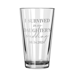 May include: A clear glass pint tumbler featuring the etched text I SURVIVED my DAUGHTER'S wedding 10.14.2024. The design uses a combination of bold block lettering and a cursive script font, centered on the front surface of the drinking vessel.
