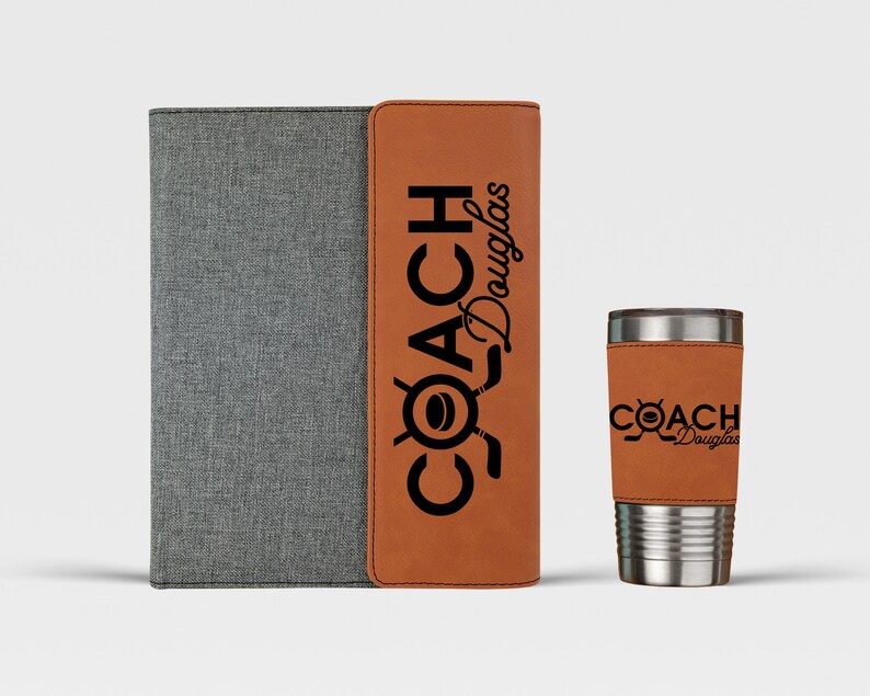 May include: A brown leatherette folder with a gray fabric cover and the text "COACH Douglas" in black. Next to it is a brown leatherette insulated tumbler with the same text.