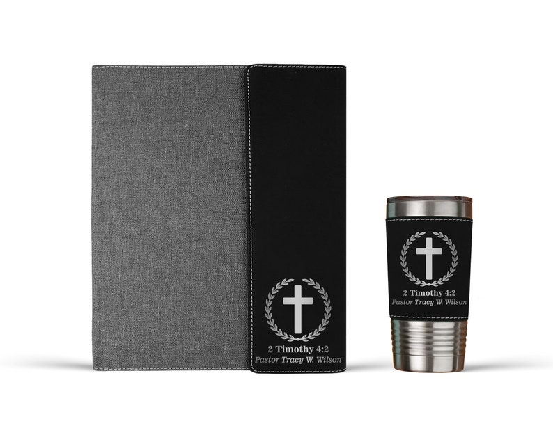 May include: A black leather journal with a gray fabric cover and a matching black leather tumbler with a silver cross and wreath design. The tumbler has the text "2 Timothy 4:2 Pastor Tracy W. Wilson" engraved on it.
