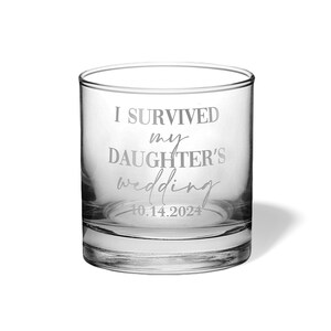 May include: A clear glass tumbler featuring the etched text I SURVIVED my DAUGHTER'S wedding and the date 10.14.2024. The vessel has a thick base and straight sides, with the white lettering clearly visible against the transparent glass surface.