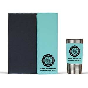 Pu&ograve; includere: Un taccuino nero con un pannello verticale azzurro che presenta un emblema nero dei vigili del fuoco e il testo CHIEF MIGLIACCIO FAIRVIEW FIRE DEPT. Accanto c'&egrave; un bicchiere in acciaio inossidabile con una custodia azzurra abbinata e l'emblema.