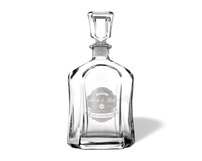 May include: A clear glass decanter with a stopper and a personalized label that reads "Mark & Bella, 50 Years, Est. 1973, Happy Anniversary".