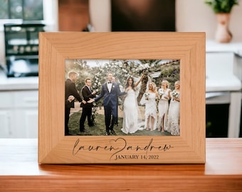 May include: A wooden picture frame with a photo of a wedding party. The frame is engraved with the names "Lauren & Andrew" and the date "January 14, 2022".