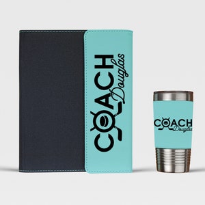May include: A black and blue personalized notebook and a stainless steel tumbler with a blue and black design. The notebook and tumbler both have the text "COACH Douglas" printed on them.