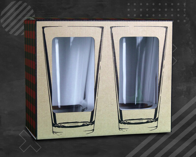 May include: A rectangular cardboard box containing two clear glass tumblers visible through die-cut windows. The packaging features a tan front panel with black line-art illustrations of the glasses and a red and black buffalo plaid side pattern.