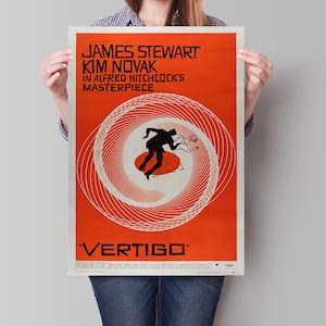 May include: A vintage movie poster for the film "Vertigo" starring James Stewart and Kim Novak. The poster features a red background with a swirling black and white design and the title "Vertigo" in white text.