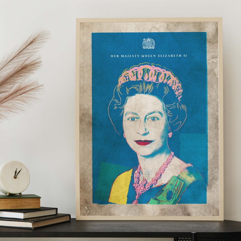 May include: A framed print of Queen Elizabeth II in a pop art style. The background is blue, and the queen is wearing a pink crown and a necklace. The text "HER MAJESTY QUEEN ELIZABETH II" is at the top of the print.