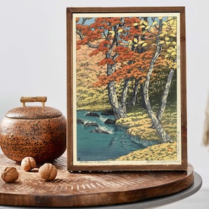 May include: A framed woodblock print of a Japanese landscape with a river and trees in autumn colors. The print is titled "Autumn in Ogawa" and signed "Hiroshi Yoshida".