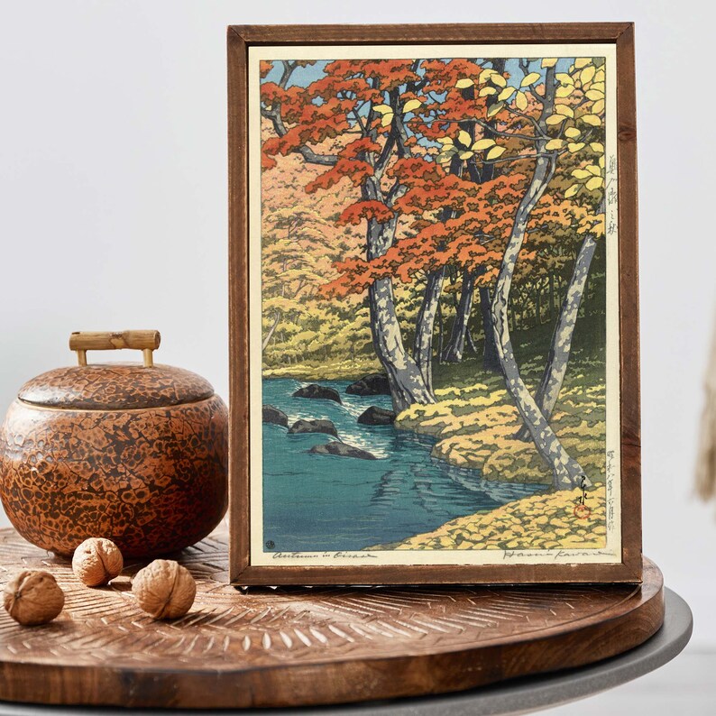 May include: A framed woodblock print of a Japanese landscape with a river and trees in autumn colors. The print is titled "Autumn in Ogawa" and signed "Hiroshi Yoshida".