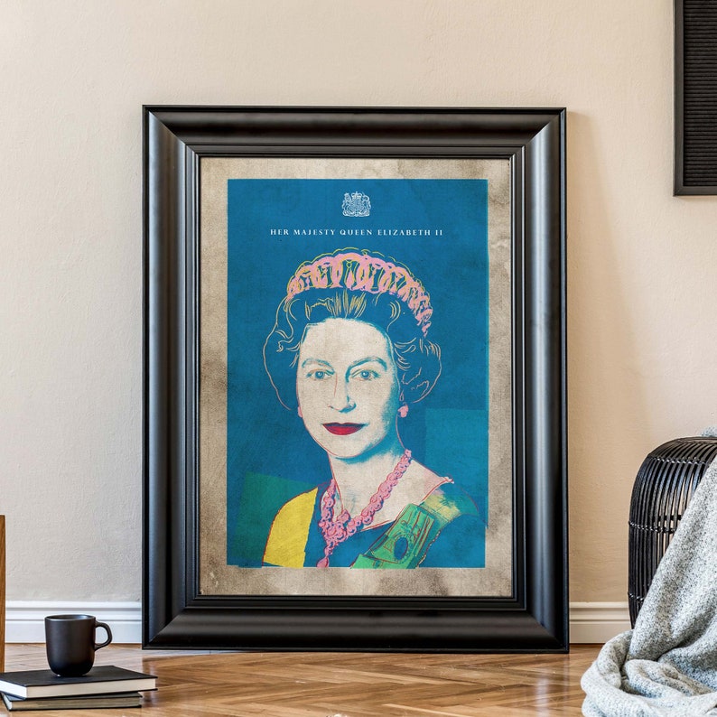 May include: A framed print of Queen Elizabeth II in a pop art style. The background is blue and the queen is wearing a pink crown and a necklace. The text "HER MAJESTY QUEEN ELIZABETH II" is at the top of the print.