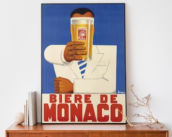Op de afbeelding: Vintage poster voor het bier Biere de Monaco. Een man houdt een glas bier voor zijn gezicht, met het bieretiket zichtbaar. De tekst "Biere de Monaco" staat in rode letters op een witte achtergrond.