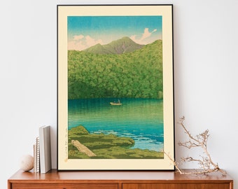 May include: A framed print of a Japanese woodblock print depicting a serene lake scene with a mountain in the background. A small boat with two figures is on the lake. The print is in shades of blue, green, and brown.