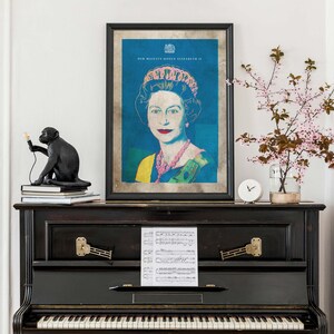 May include: A black and white framed print of Queen Elizabeth II in a pop art style. The print is on a black piano with sheet music on top. The print has the text "HER MAJESTY QUEEN ELIZABETH II" at the top.