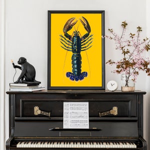 Puede incluir: Una ilustraci&oacute;n vintage de una langosta azul sobre un fondo amarillo. La langosta est&aacute; representada en un estilo realista y detallado, con las garras levantadas. La imagen est&aacute; enmarcada y se muestra en un piano negro.
