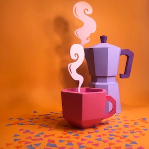 May include: A purple paper coffee pot with a pink paper coffee cup and white paper steam rising from the cup. The coffee pot and cup are sitting on an orange surface with scattered blue, pink, and orange paper triangles.