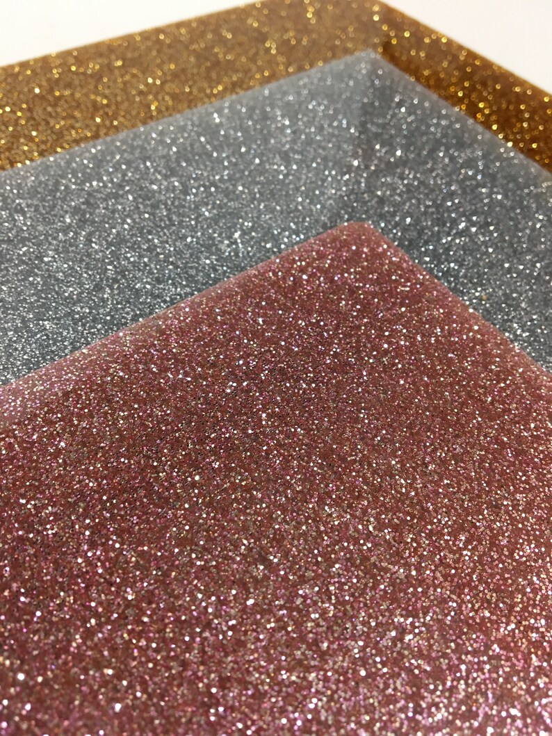Puede incluir: Tres hojas de papel de purpurina en dorado, plateado y oro rosa. Las hojas est&aacute;n apiladas una encima de la otra, con la hoja dorada en la parte superior y la hoja de oro rosa en la parte inferior.
