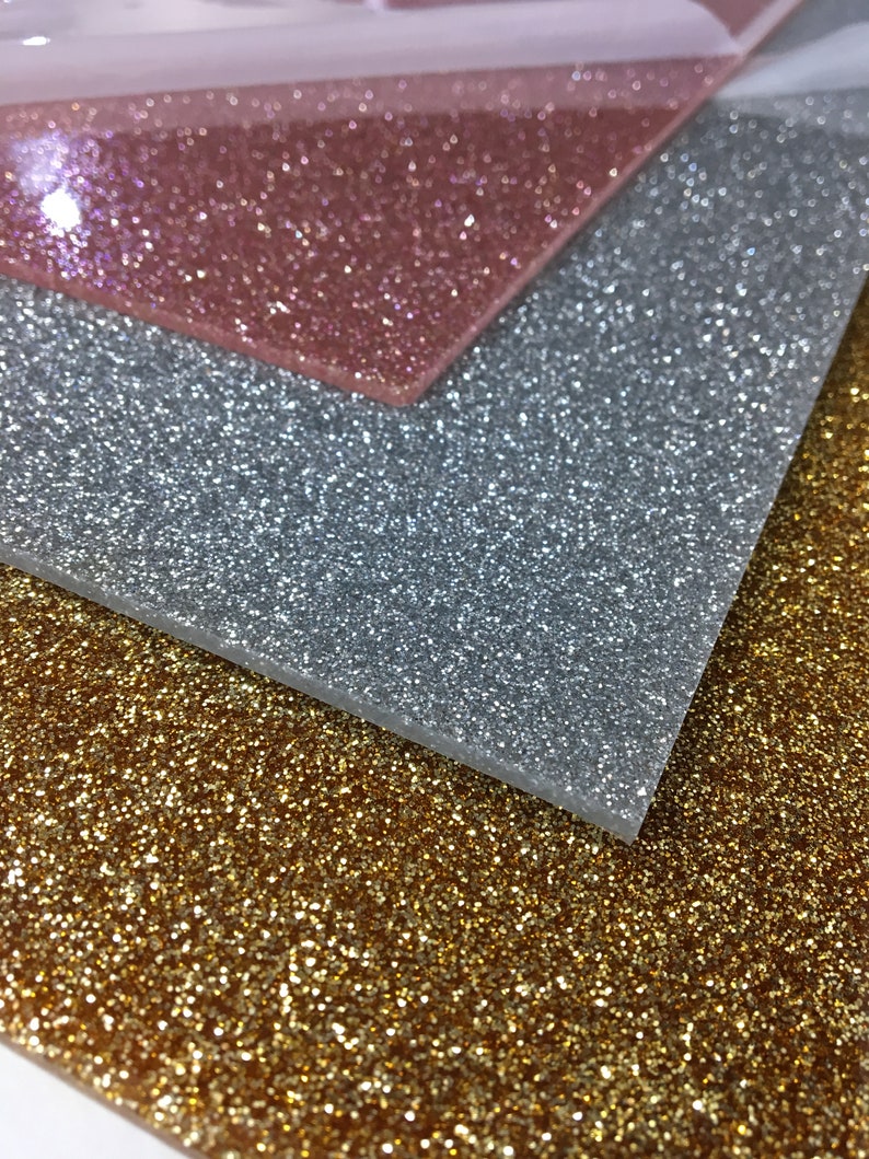 Puede incluir: Tres hojas de papel de purpurina en dorado, plateado y rosa dorado. Las hojas est&aacute;n apiladas una encima de la otra.