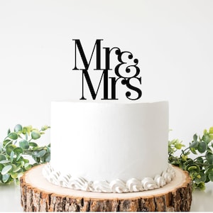 May include: White wedding cake with a black "Mr & Mrs" topper.