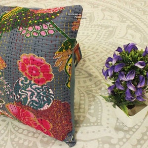 May include: A gray cotton pillow cover with a floral pattern in shades of pink, green, and yellow. The pillow cover is quilted and has a fringed edge. The text "Multimate Collection" is visible in the upper right corner of the pillow.