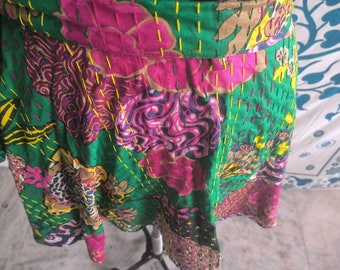 May include: A colorful wrap skirt with a patchwork design featuring floral patterns in shades of pink, green, yellow, and brown. The skirt is made of cotton and has a unique hand-stitched detail.