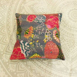 May include: A gray cotton pillow cover with a floral pattern in shades of pink, red, yellow, and green. The pillow cover has a quilted design and the text "Ultimate Collection" is printed in the top left corner.