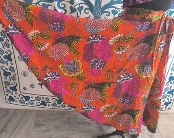 May include: A bright orange wrap skirt with a floral print in shades of pink, purple, and green. The skirt is made of a soft, lightweight fabric and has a flowing silhouette.
