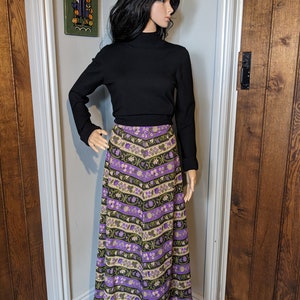 Puede incluir: Una falda larga y fluida con un estampado floral morado y verde. La falda est&aacute; hecha de una tela suave y tejida y tiene una cintura alta.