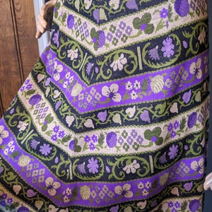 Puede incluir: Una falda morada, verde y negra con un estampado floral. La falda est&aacute; hecha de tejido tejido y tiene un estilo vintage.